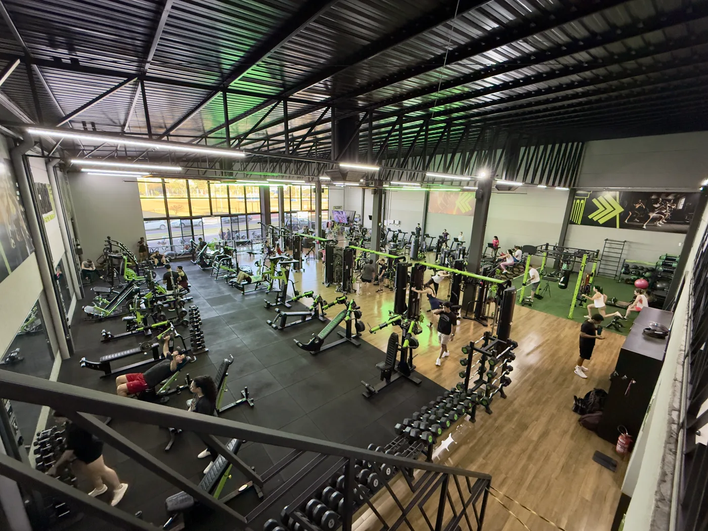 Vista do mezanino sobre o salão da Ágora, com dezenas de alunos treinando em aparelhos, halteres e área de funcional